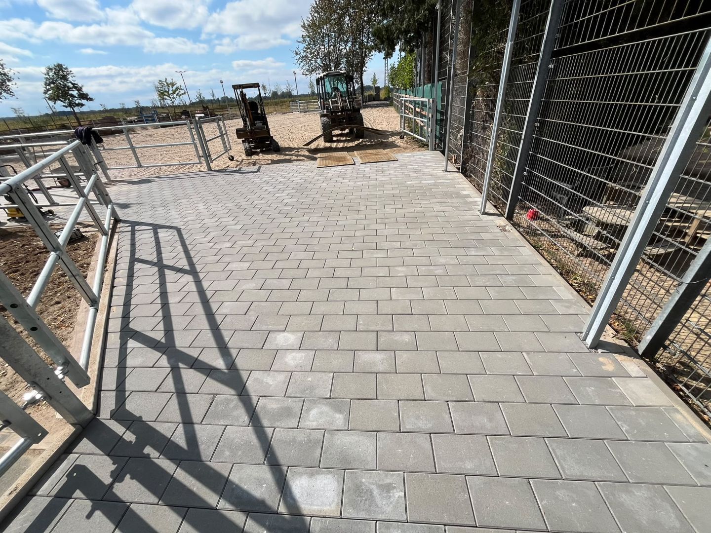 Verlegte Plattenfläche entlang einer Hauswand mit Metallgeländer